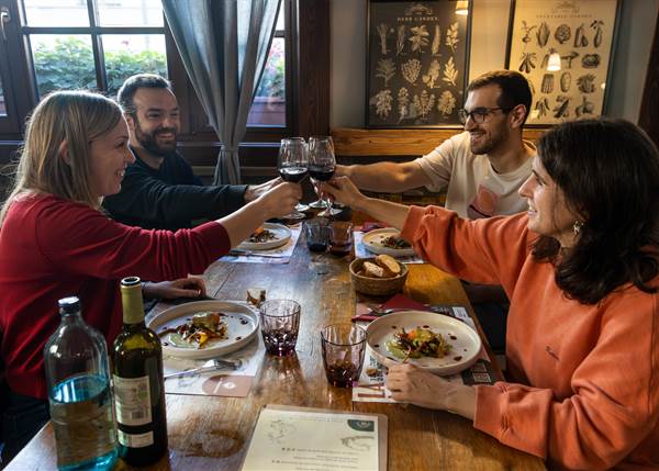 Cuatro personas brindando en una mesa con platos de comida