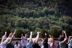 Participantes levantando las manos durante una sesión de yoga al aire libre.
