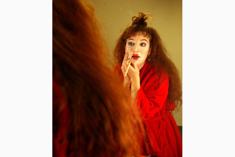 Mujer con cabello rizado y maquillaje de clown en un espejo