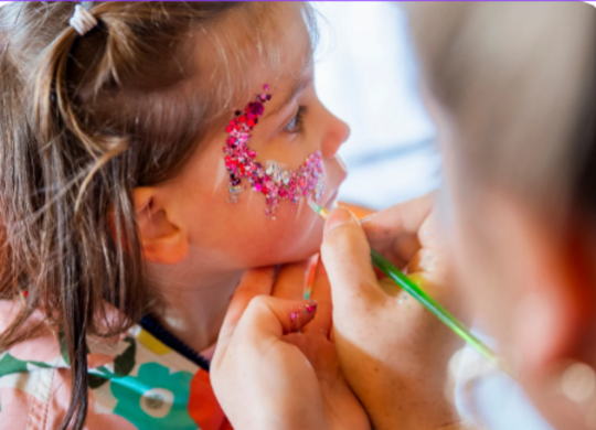 Niña recibiendo maquillaje colorido para el Carnaval