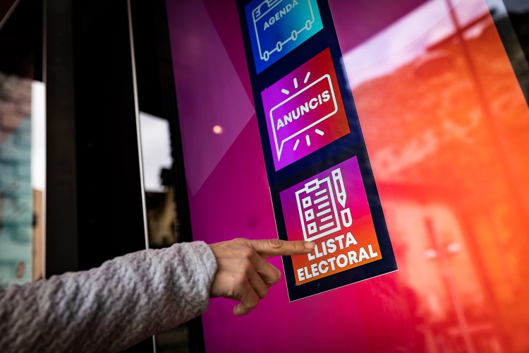 Persona señalando un cartel de lista electoral en Andorra la Vella