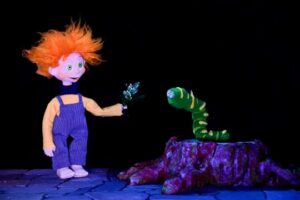 Marioneta con cabello rizado y oruga en un espectáculo infantil