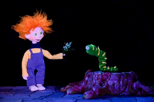 Marioneta con cabello rizado y oruga en un espectáculo infantil