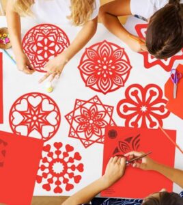 Niños creando figuras de papel rojo para el Año Nuevo Chino
