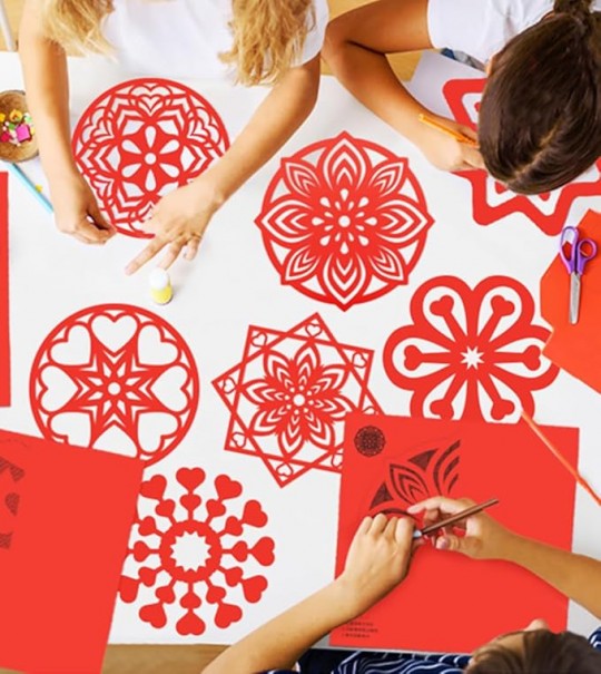 Niños creando figuras de papel rojo para el Año Nuevo Chino
