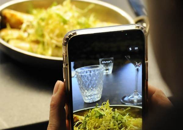 Persona tomando una foto de un plato de comida en un restaurante