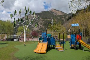 Parque de Prat de Call con juegos infantiles y paisaje montañoso
