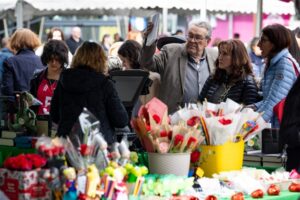 Visitantes en la Fira de Sant Jordi con libros y rosas en la plaza del Poble