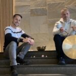 Dos hombres sentados en escaleras con instrumentos de sanación