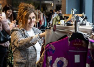 Mujer sonriendo mientras revisa ropa en un evento de Vide Dressing.