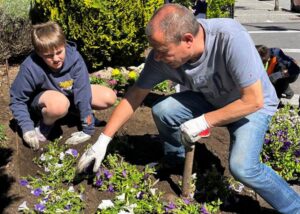 Niños y adultos plantando flores en un jardín comunitario