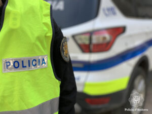 Policía de Andorra con chaleco amarillo y vehículo policial de fondo